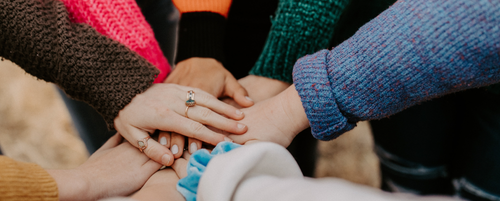 Photo: Hands joined together in a huddle.