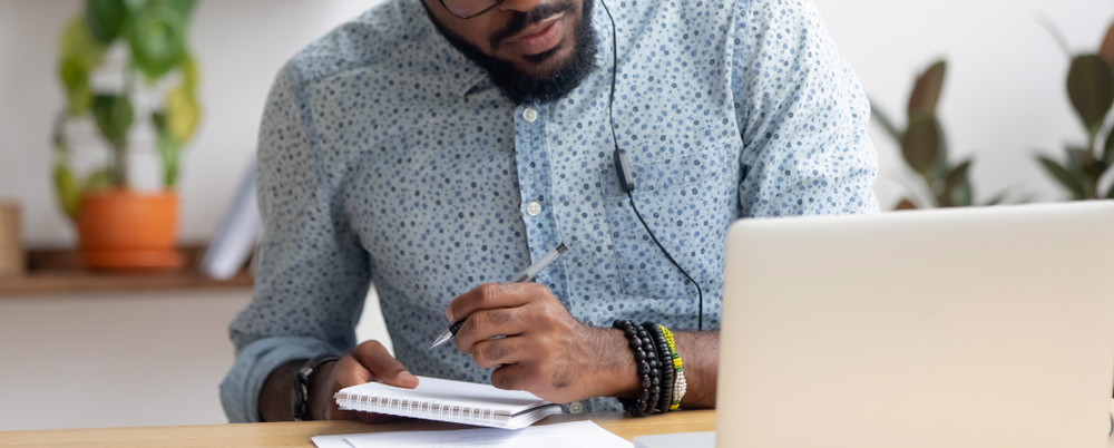 Man with headphones learning and taking notes